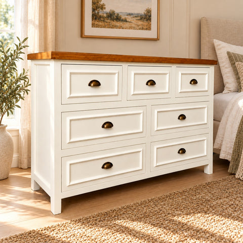 Cómoda Aval Deluxe de MGR Muebles con 7 cajones, acabado blanco y cubierta de madera natural en un dormitorio rústico.